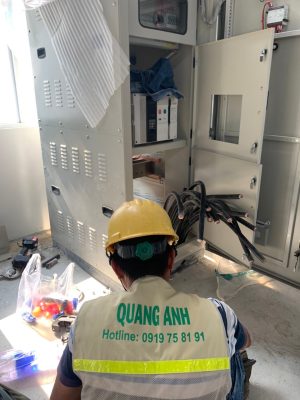 Worker at an electrical cabinet door with meters and protection controls in the QuangAnhcons archive