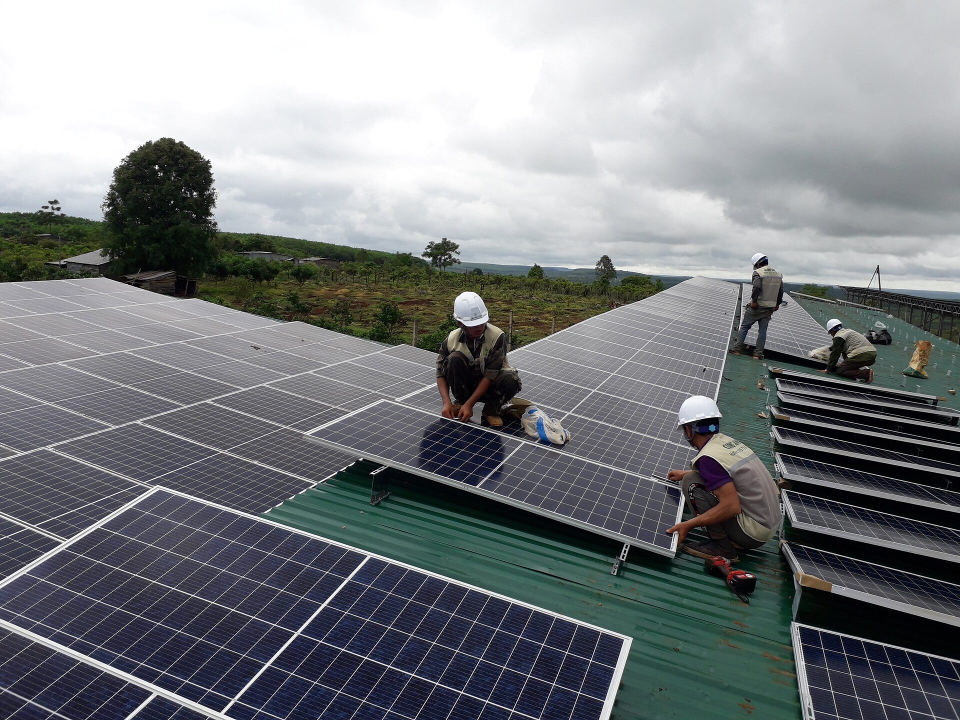 Workers installing photovoltaic modules on an industrial rooftop