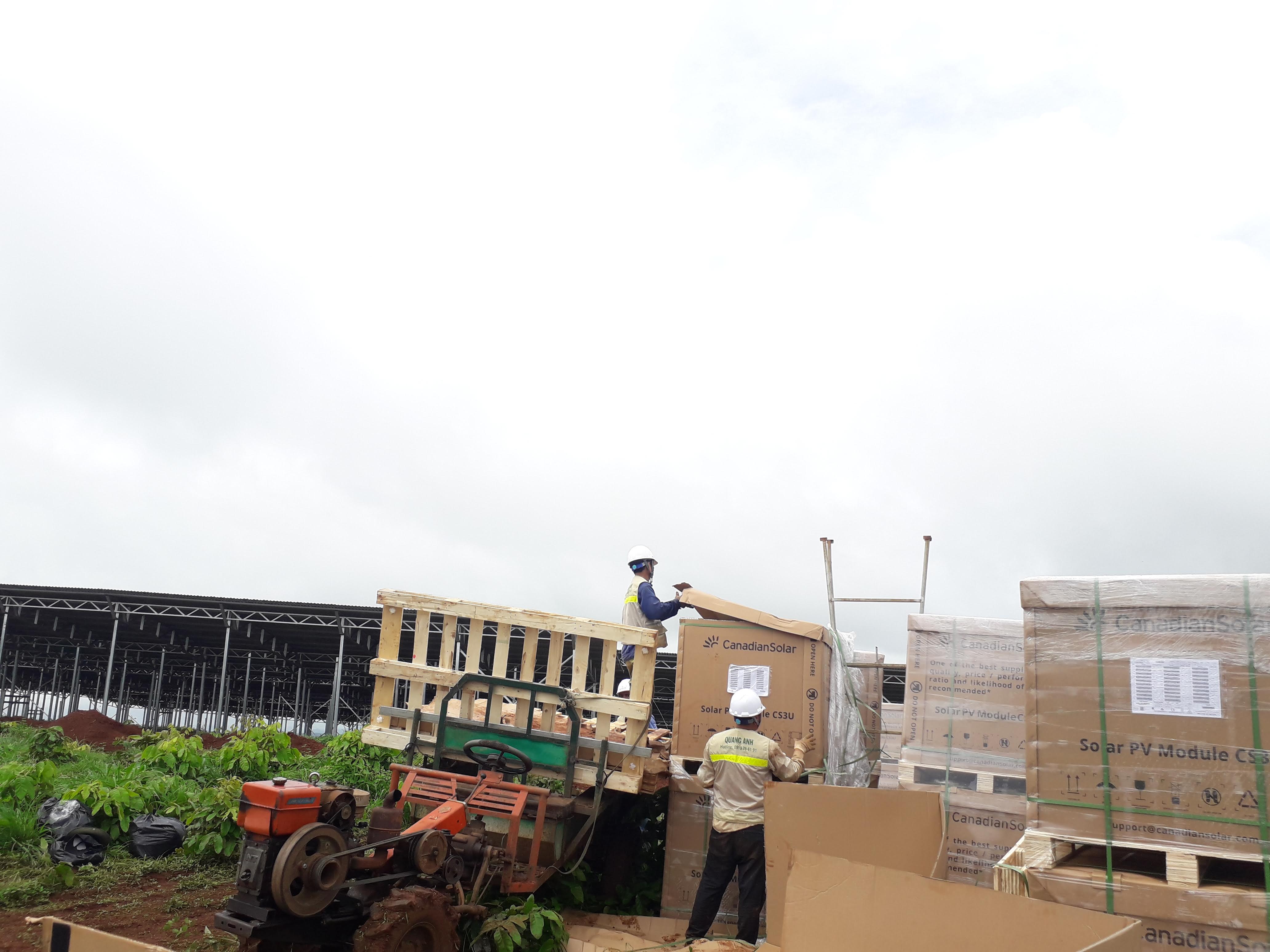 QuangAnhcons crew handling packaged photovoltaic modules at an industrial site