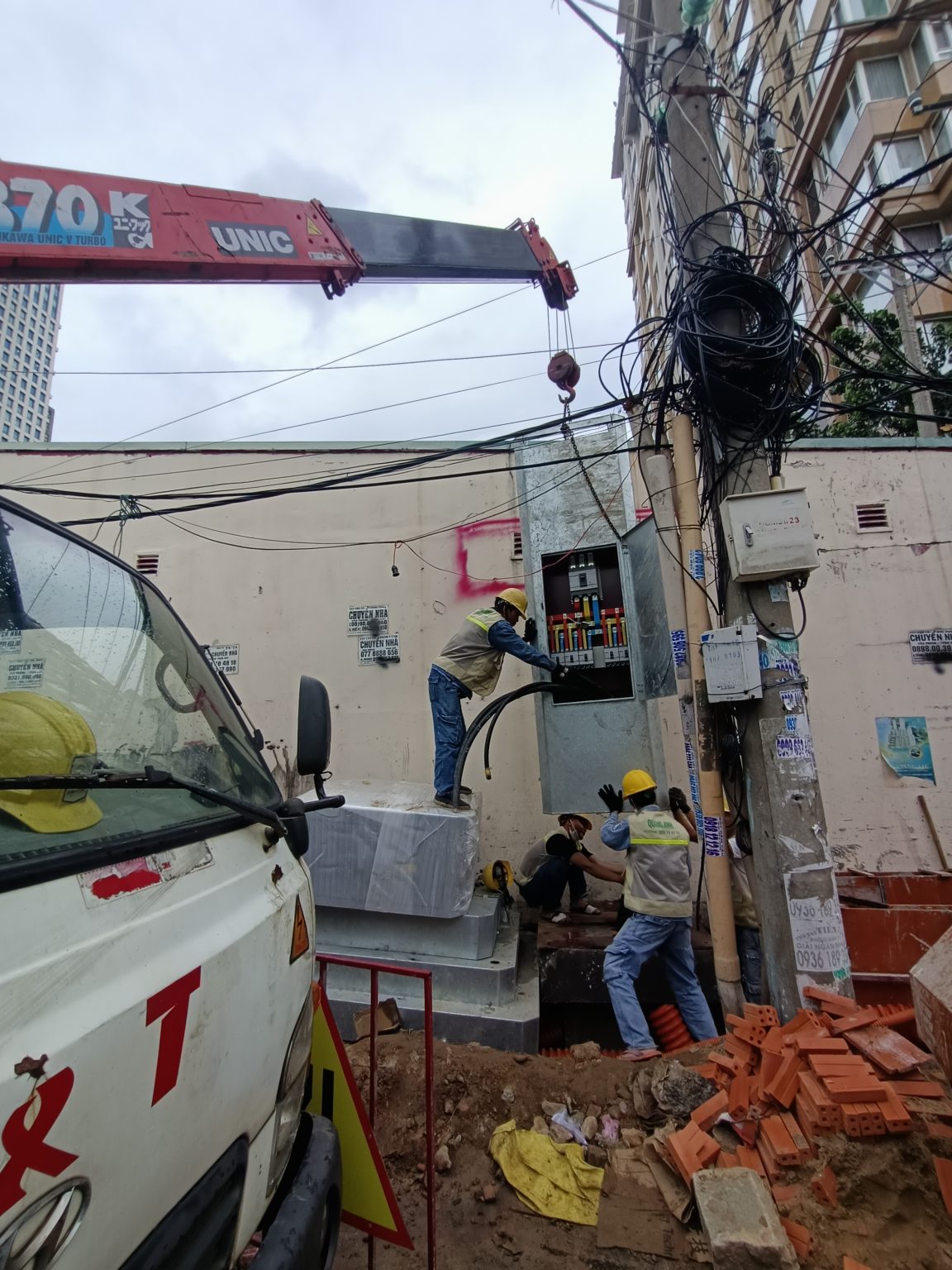 QuangAnhcons crew working at an electrical cabinet beside a constrained street corridor