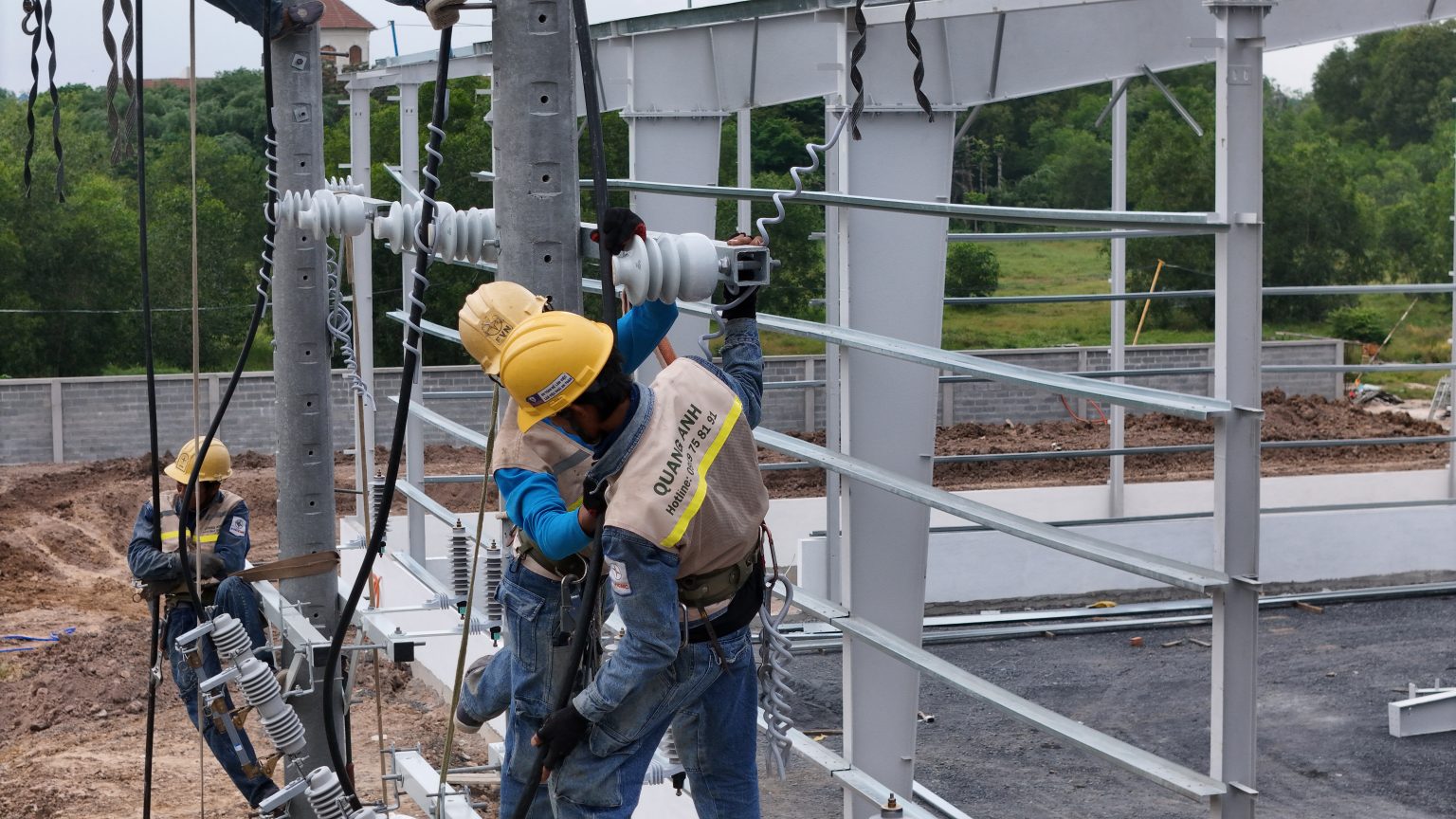 QuangAnhcons workers installing insulators on outdoor electrical support structures