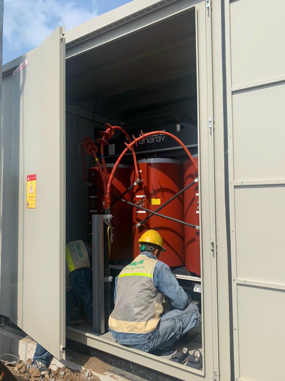Historical field photograph of electrical technician working at an enclosed transformer equipment bay