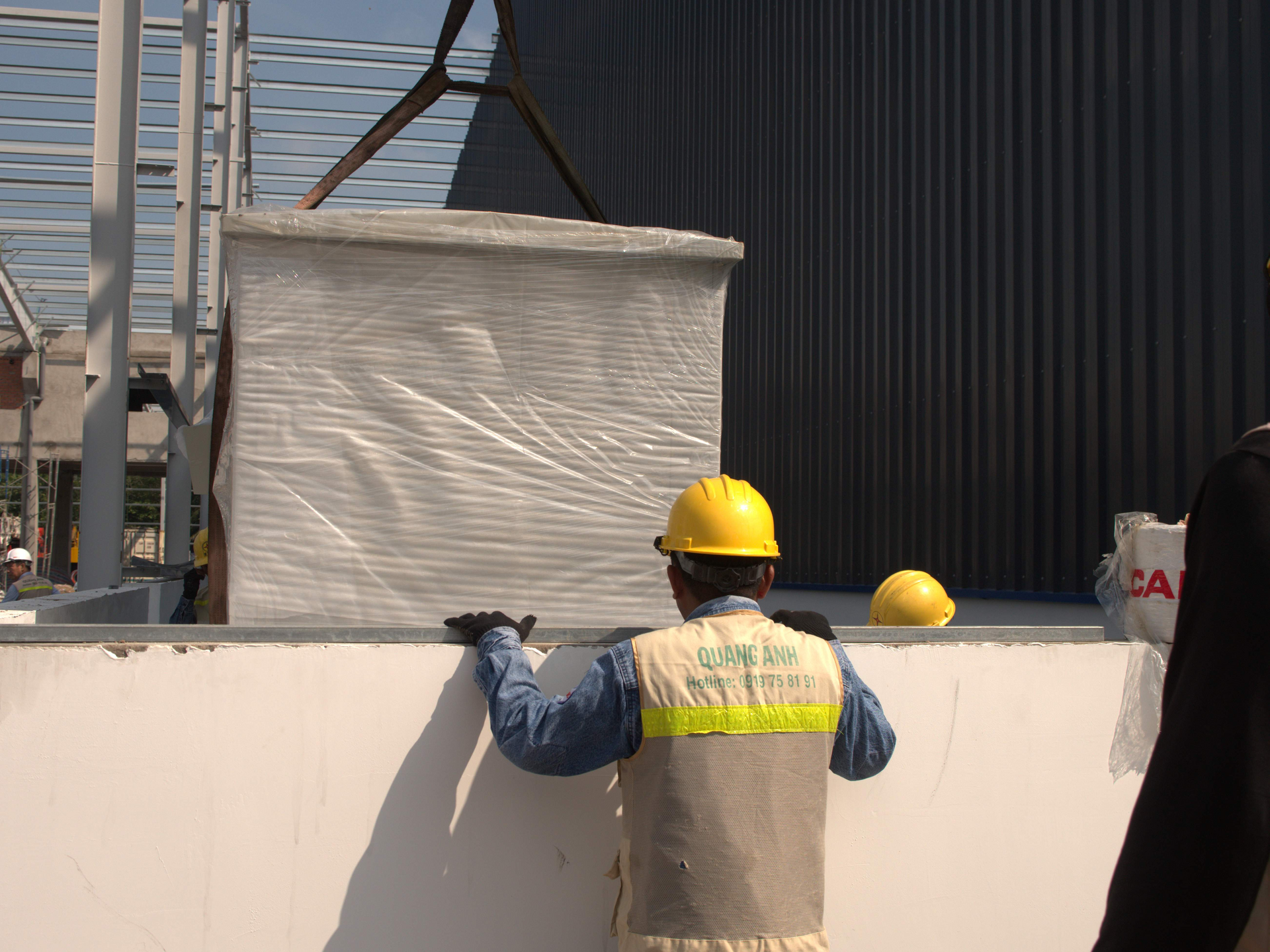 QuangAnhcons archive showing a wrapped electrical enclosure and site personnel